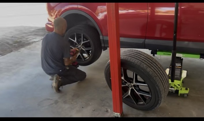 Keys Quick Lube technician removing a wheel from a red SUV
